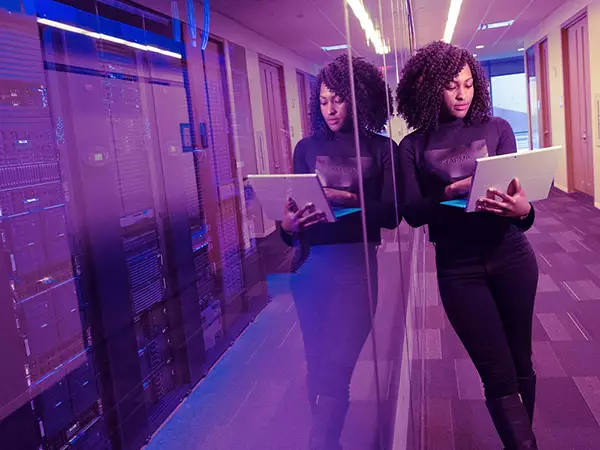 Woman on computer next to servers